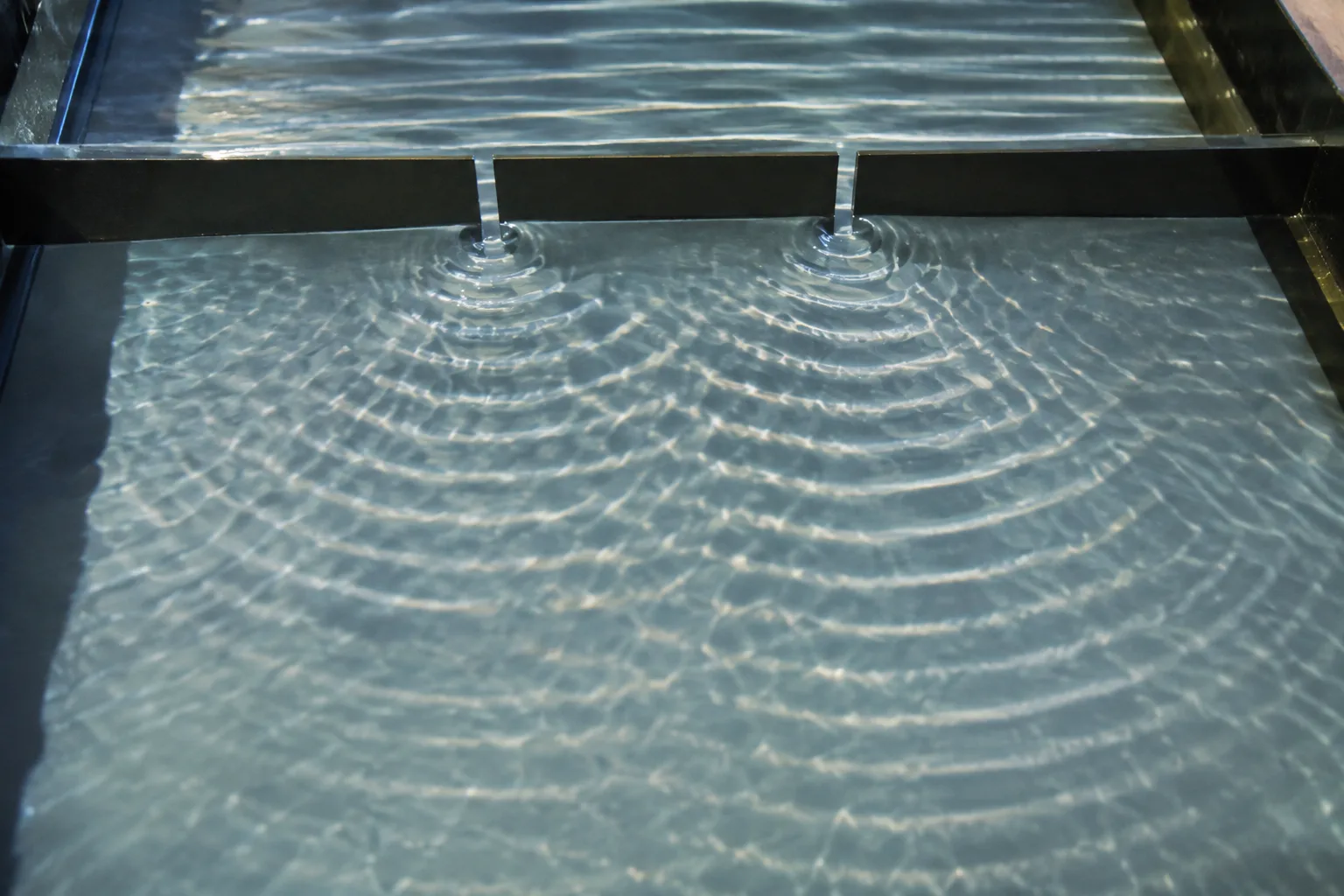 Ripples from two openings overlap, producing regions of strong motion and near-still water.